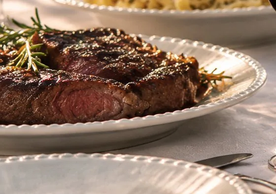Carne grelhada fatiada com ramos de alecrim.