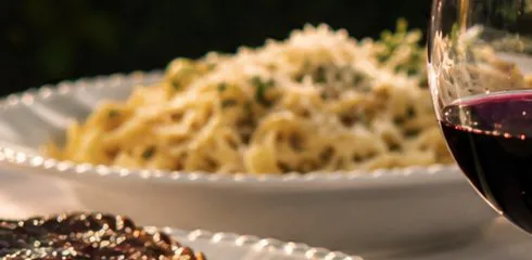 Prato de massa com ervas e queijo ralado.